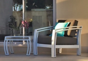 White aluminium club armchair with sand cushions and small side table on the porch of a modern house in Marbella, Malaga